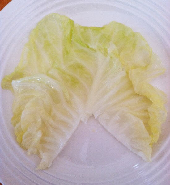 Cut the roughest part of stem out of the cabbage leaf about 2 inches from the bottom. This is what it should look like. Put your filling at the top. Roll once. Fold in both outer edges and then continue to roll up until they are in a nice, neat roll.